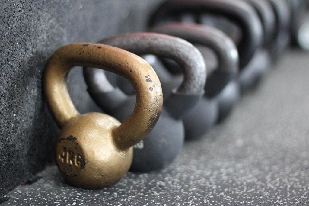 Man voert thuis trainen met dumbbells en kettlebells uit tijdens circuittraining workout